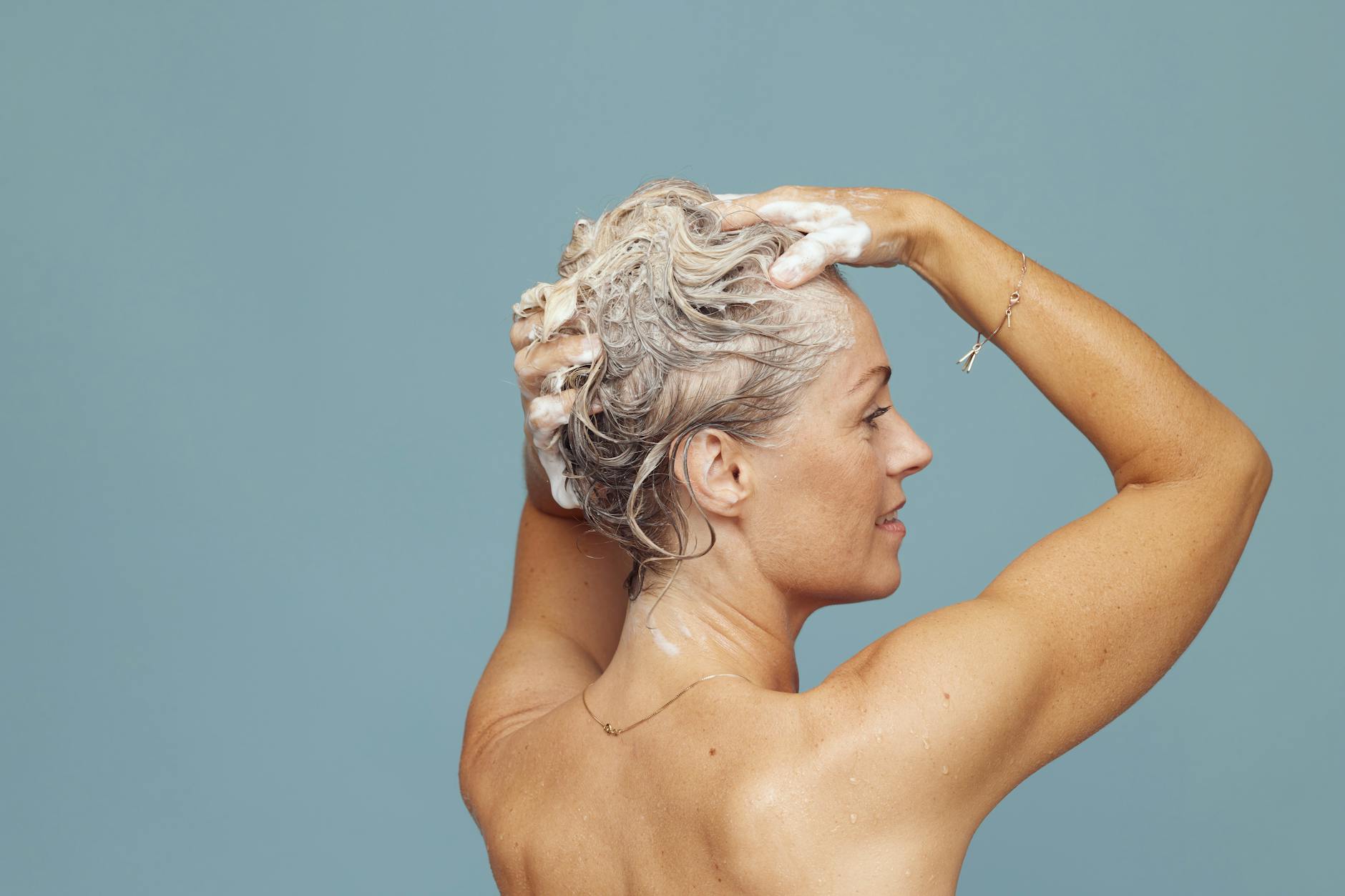 woman washing hair with shampoo indoors