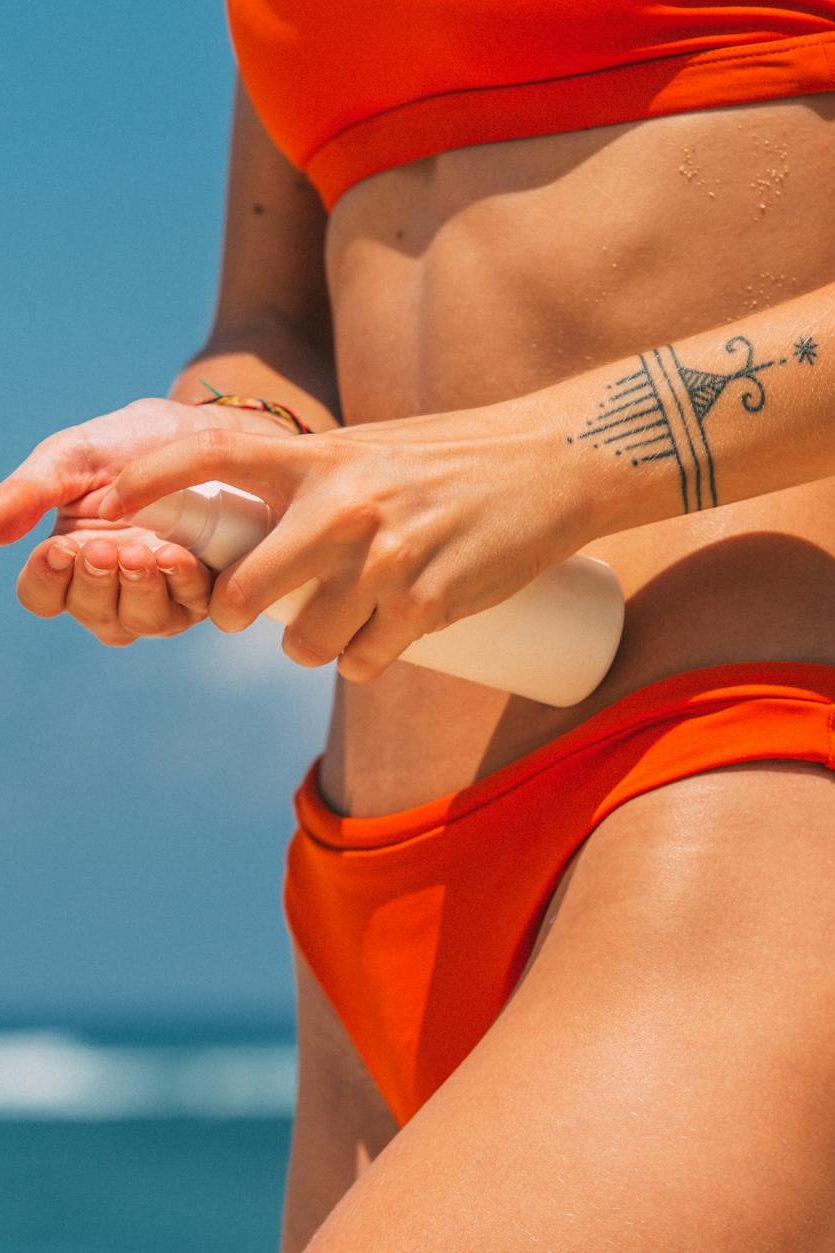 close up of woman in bikini applying sunscreen